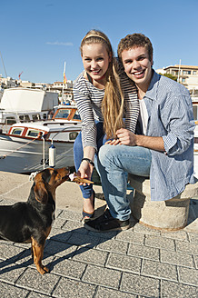 Spain, Mallorca, Couple feeding ice cream to stray dog, smiling, portrait - MFPF000062