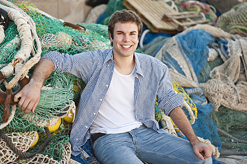 Spain, Mallorca, Young man at harbour with fishing nets, smiling, portrait - MFPF000063