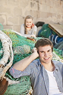 Spain, Mallorca, Couple at harbour with fishing nets, smiling, portrait - MFPF000064