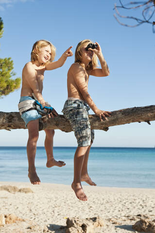 Spanien, Mallorca, Kinder sitzen auf Baum, lizenzfreies Stockfoto