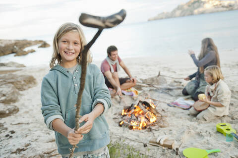 Spain, Mallorca, Friends with sausages at camp fire on beach stock photo