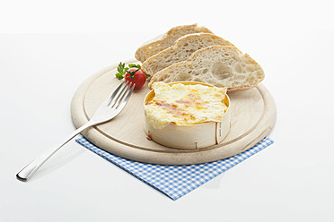 Gebackener Ofenkäse mit Brot auf Holzplatte - MAEF004394