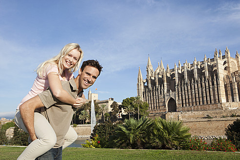 Spanien, Mallorca, Palma, Lächelndes Paar mit Kathedrale Santa Maria im Hintergrund, Porträt - SKF000881