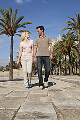 Spanien, Mallorca, Palma, Pärchen geht lächelnd eine Allee entlang - SKF000885