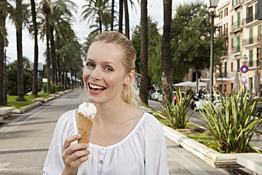 Spain, Mallorca, Palma, Young woman eating ice cream, smiling, portrait - SKF000937