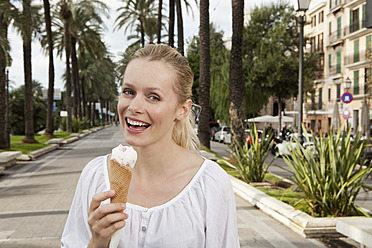 Spanien, Mallorca, Palma, Junge Frau isst Eiscreme, lächelnd, Porträt - SKF000937