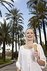 Spain, Mallorca, Palma, Young woman eating ice cream, smiling - SKF000940