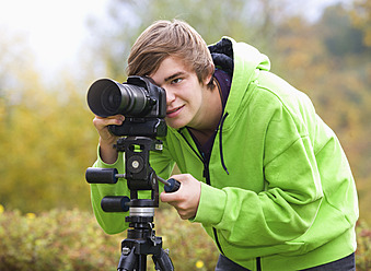 Austria, Young man taking photograph, smiling - WWF002137