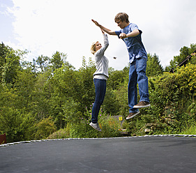 Austria, Young man and woman jumping on trampoline - WWF002138