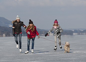 Austria, Teenage girls doing ice skating with dog - WWF002290