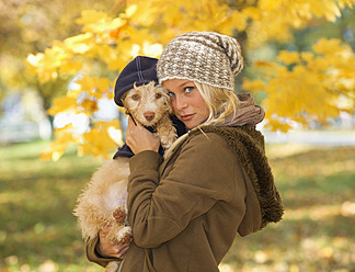 Austria, Young woman holding dog in autumn, portrait, close up - WWF002152