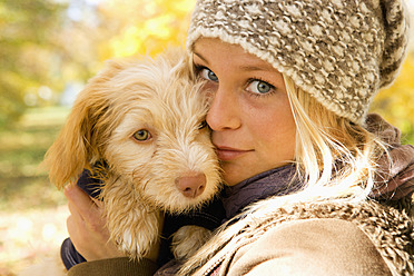 Austria, Young woman holding dog in autumn, portrait, close up - WWF002153