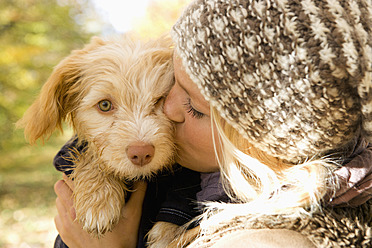 Austria, Young woman kissing dog in autumn, close up - WWF002154