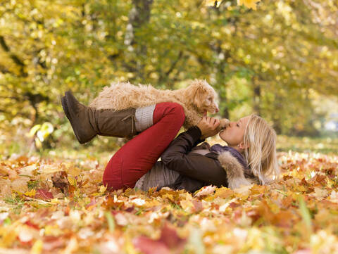 Österreich, Junge Frau spielt Hund auf Herbstblatt, lizenzfreies Stockfoto