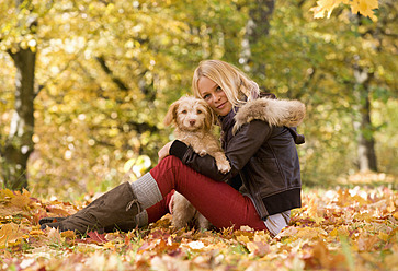 Österreich, Junge Frau spielt Hund auf Herbstblatt, lächelnd, Porträt - WWF002156