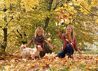 Austria, Sisters playing with dog in autumn - WWF002159