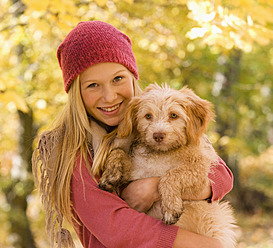 Österreich, Jugendliches Mädchen hält Hund im Herbst, lächelnd, Porträt - WWF002162