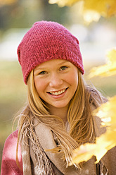 Austria, Close up of teenage girl with maple leaf, smiling - WWF002164
