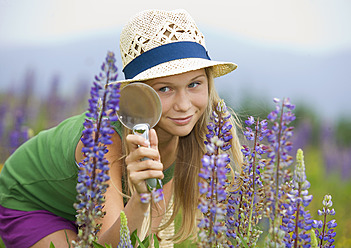 Österreich, Jugendliches Mädchen betrachtet Lupine durch ein Vergrößerungsglas - WWF002222