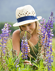 Österreich, Jugendliches Mädchen betrachtet Lupine durch ein Vergrößerungsglas - WWF002223