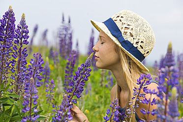 Austria, Teenage girl smelling lupine flower - WWF002224