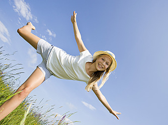 Austria, Teenage girl doing gymnastics in field, smiling, portrait - WWF002229