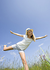 Austria, Teenage girl doing gymnastics in field, smiling, portrait - WWF002231