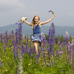 Austria, Teenage girl running in lupine field, smiling, portrait - WWF002235