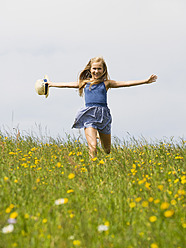 Austria, Teenage girl running in field, smiling, portrait - WWF002236