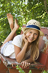 Austria, Teenage girl relaxing on bench in garden, portrait - WWF002245