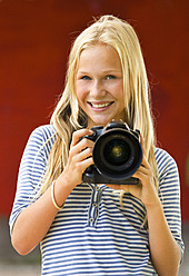 Austria, Teenage girl with camera, smiling, portrait - WWF002257