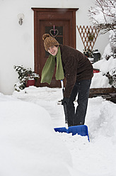 Österreich, Junger Mann beim Schneeschaufeln vor dem Haus, Porträt - WWF002136