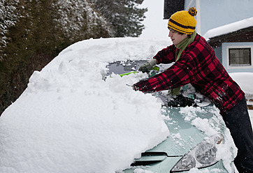 Österreich, Junger Mann reinigt Schnee auf Auto - WWF002125