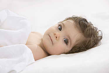 Baby girl lying on back, covered with blanket, portrait - SMOF000458