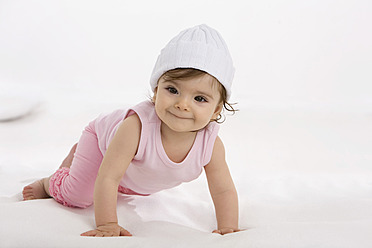 Baby girl crawling on baby blanket, smiling - SMOF000464