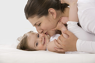 Mother cuddling daughter, smiling - SMOF000480