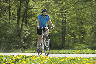 Deutschland, Bayern, München, Mittlere erwachsene Frau fährt Elektrofahrrad - DSF000235