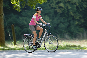 Deutschland, Bayern, München, Mittlere erwachsene Frau fährt Elektrofahrrad - DSF000237