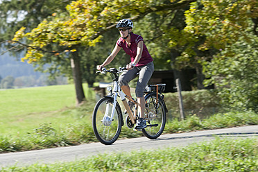 Deutschland, Bayern, Mittlere erwachsene Frau fährt Elektrofahrrad - DSF000240