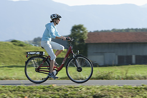 Deutschland, Bayern, Mittlere erwachsene Frau fährt Elektrofahrrad - DSF000243