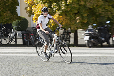 Deutschland, Bayern, München, Mittlere erwachsene Frau fährt Elektrofahrrad - DSF000248