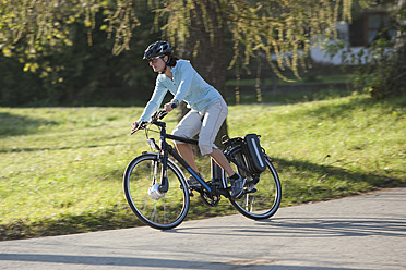 Deutschland, Bayern, Mittlere erwachsene Frau fährt Elektrofahrrad - DSF000251