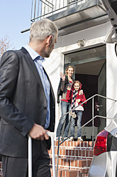 Germany, Leipzig, Father leaving for business trip while mother and daughter in background - WESTF018433