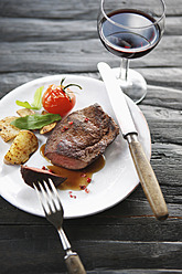 Germany, Bremen, Steak with vegetable and wine on table - KSWF000802