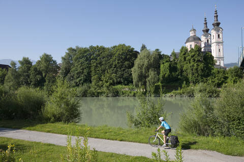 Österreich, Kärnten, Villach, Mittlere erwachsene Frau fährt Fahrrad, lizenzfreies Stockfoto