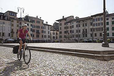 Italy, Udine, Mid adult woman riding bicycle - DSF000269