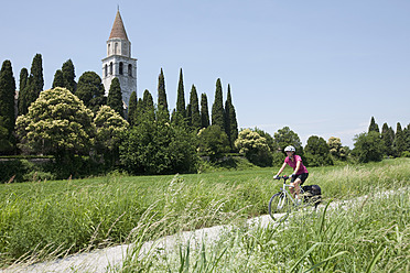 Italien, Aquileia, Mittlere erwachsene Frau fährt Fahrrad - DSF000278