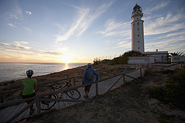 Spanien, Andalusien, Mann und Frau stehen am Leuchtturm und beobachten den Sonnenuntergang - DSF000289
