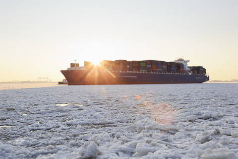 Deutschland, Hamburg, Containerschiff auf eisbedeckter Elbe, lizenzfreies Stockfoto