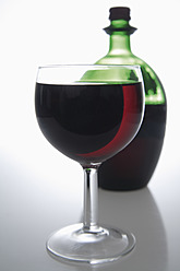 Rotwein in Glas und Flasche auf grauem Hintergrund - TCF002198